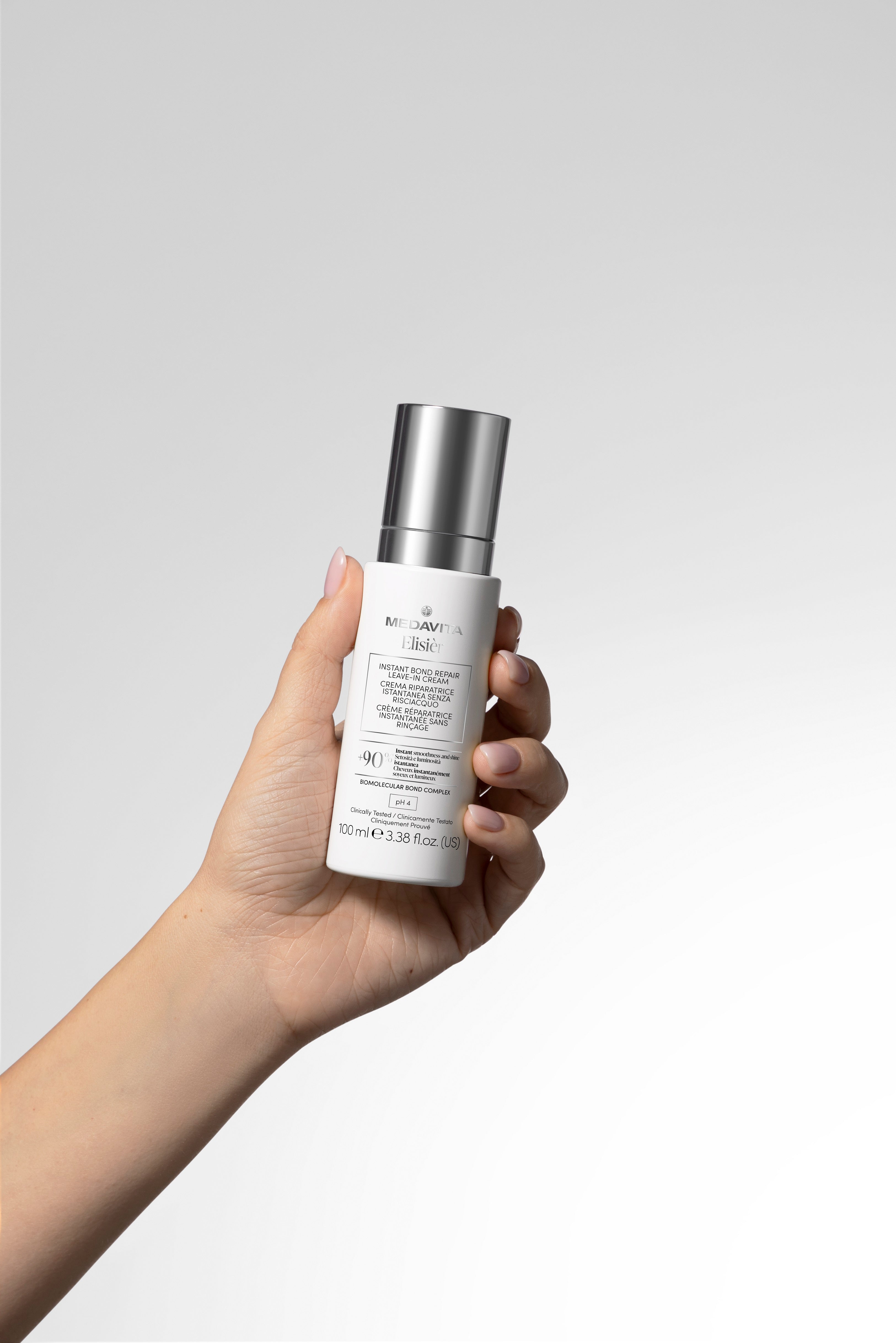 Medavita Elisièr Instant Bond Repair Leave-In Cream 100 ml ținut în mână, cremă leave-in profesională pentru repararea părului deteriorat, hidratare intensă și efect anti-frizz.